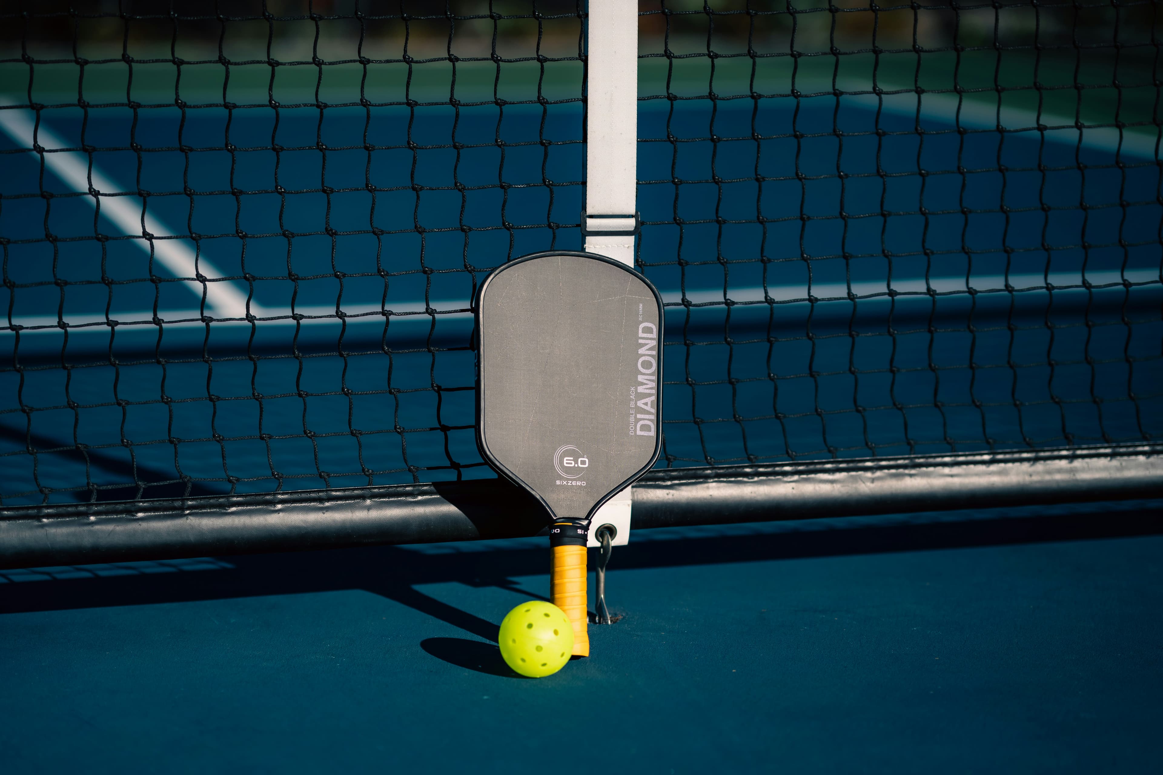 Pickleball paddle and ball on court